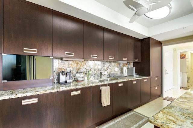 kitchen with sink, backsplash, ceiling fan, and light stone countertops