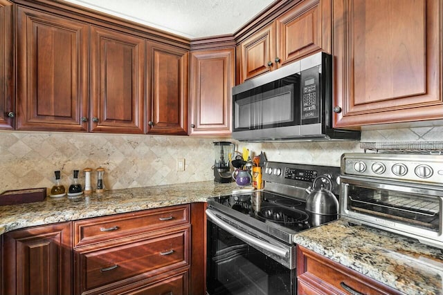 kitchen featuring decorative backsplash, light stone counters, and appliances with stainless steel finishes