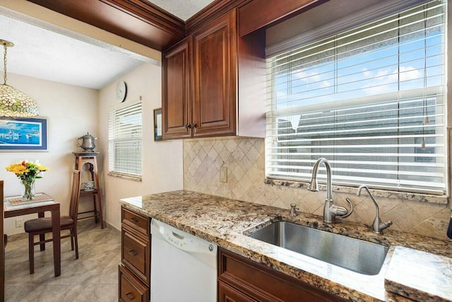 kitchen featuring light stone countertops, decorative backsplash, white dishwasher, sink, and hanging light fixtures