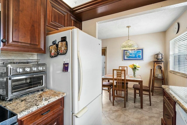 kitchen with backsplash, light stone counters, decorative light fixtures, and white appliances