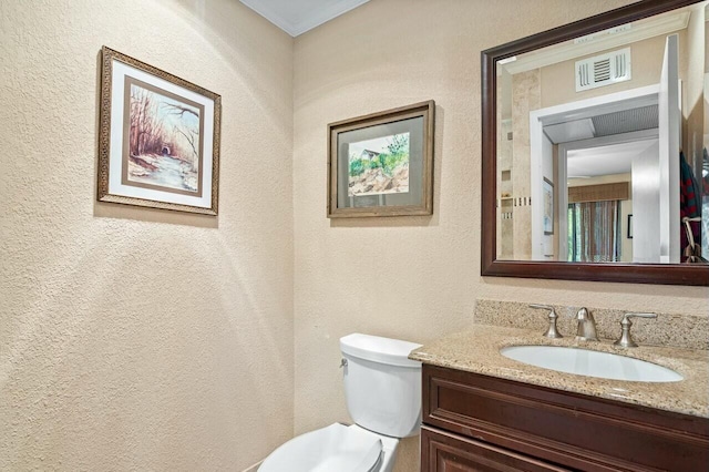 bathroom with crown molding, vanity, and toilet