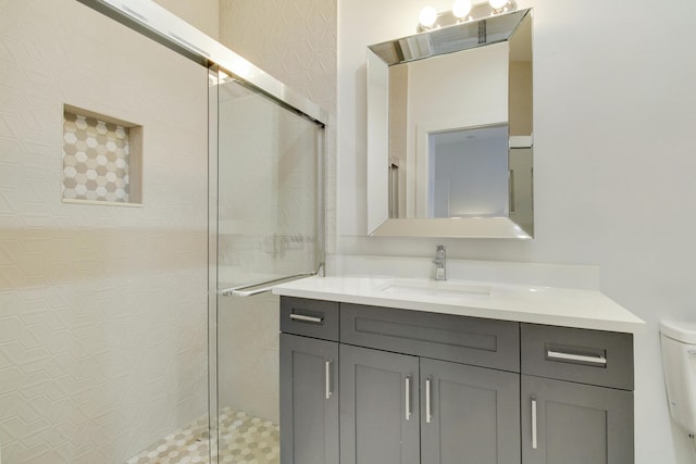 bathroom featuring a shower with door, vanity, and toilet