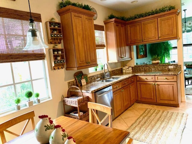 kitchen featuring dishwasher, sink, light tile patterned floors, and dark stone counters