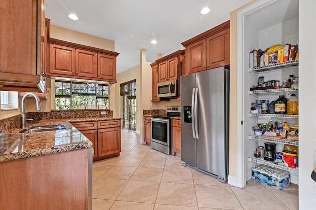 kitchen featuring light tile patterned floors, sink, appliances with stainless steel finishes, and dark stone counters