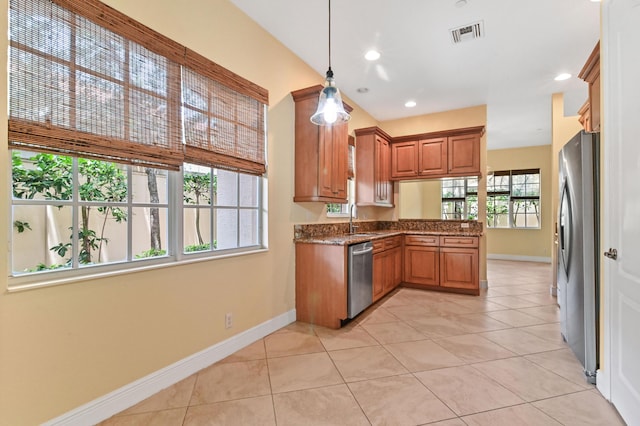 kitchen with appliances with stainless steel finishes, sink, pendant lighting, stone countertops, and light tile patterned flooring