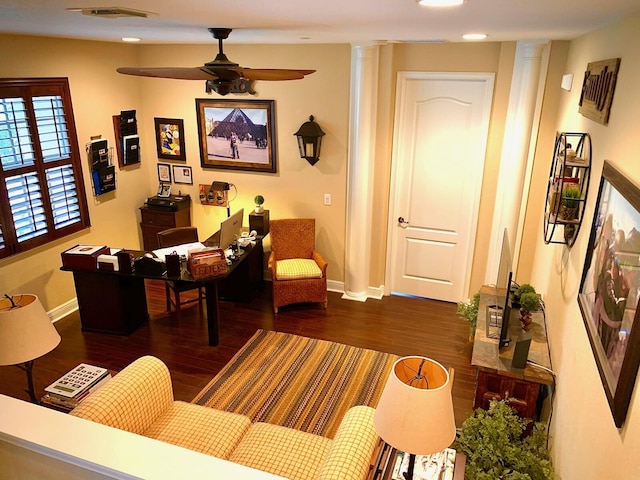 living room featuring ceiling fan, ornate columns, and dark wood-type flooring