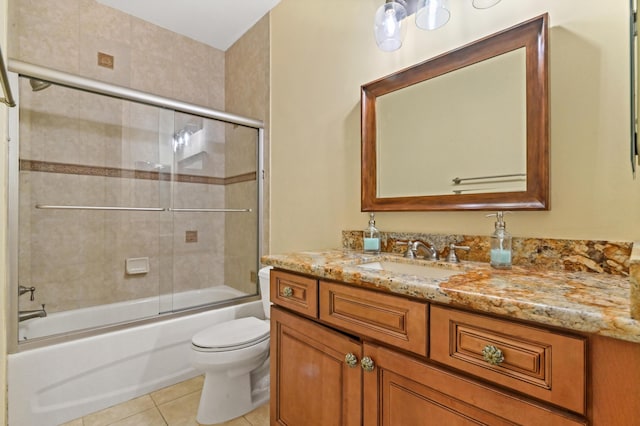 full bathroom with toilet, vanity, tile patterned floors, and bath / shower combo with glass door