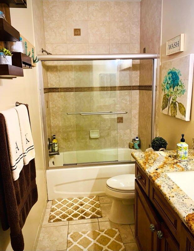 full bathroom featuring tile patterned flooring, toilet, vanity, and combined bath / shower with glass door