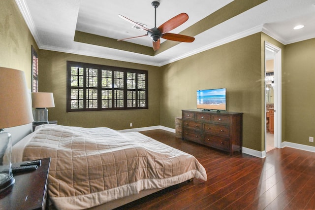 bedroom featuring dark hardwood / wood-style floors, ceiling fan, ornamental molding, and a tray ceiling