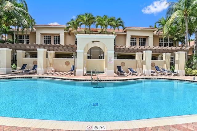 rear view of house featuring a pergola, a patio, and a community pool