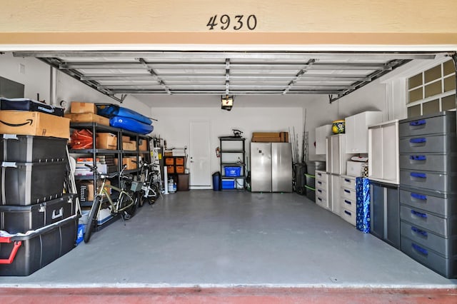 garage featuring stainless steel fridge and a garage door opener