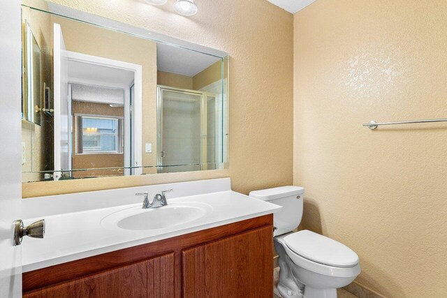 bathroom featuring an enclosed shower, vanity, and toilet