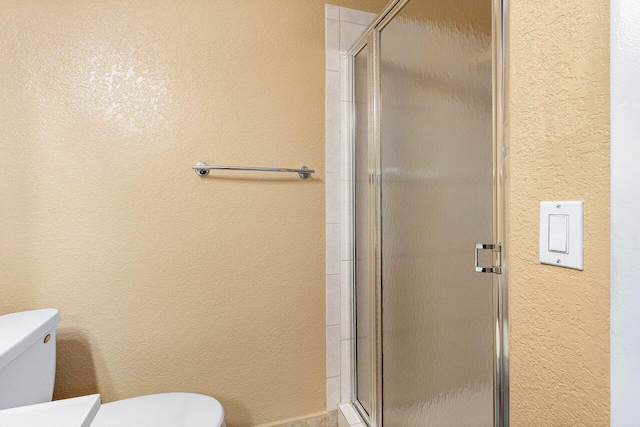 bathroom with a shower with shower door and toilet