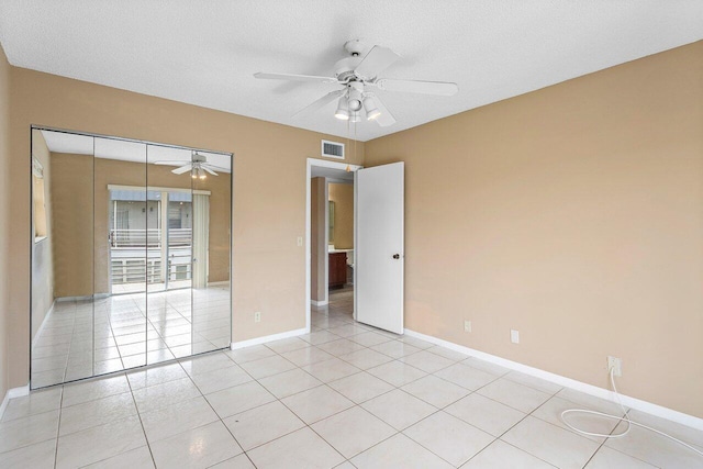 tiled spare room with a textured ceiling and ceiling fan