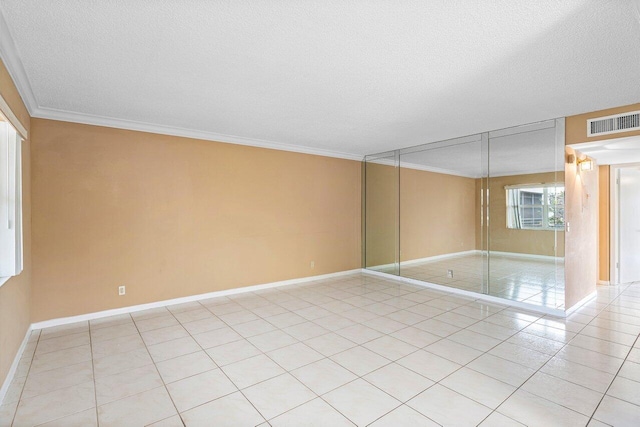 empty room featuring light tile patterned flooring, crown molding, and a textured ceiling