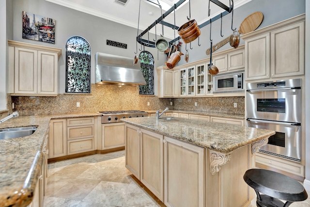 kitchen with sink, wall chimney exhaust hood, stainless steel appliances, light stone counters, and ornamental molding