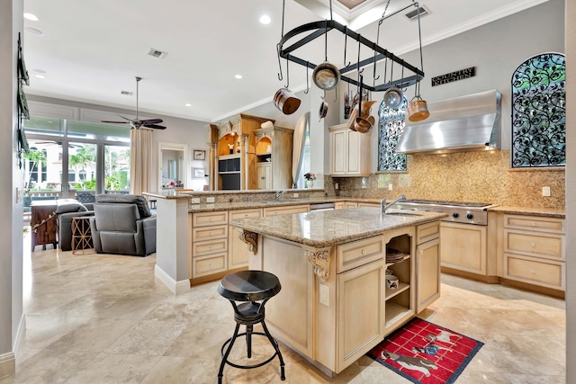 kitchen with stainless steel appliances, wall chimney range hood, kitchen peninsula, a breakfast bar area, and a kitchen island with sink