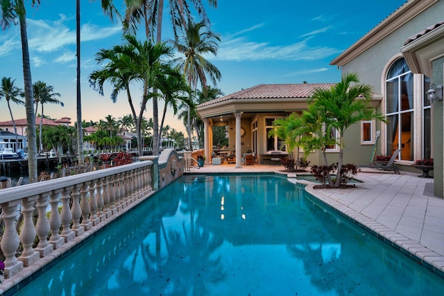 pool at dusk with a patio area