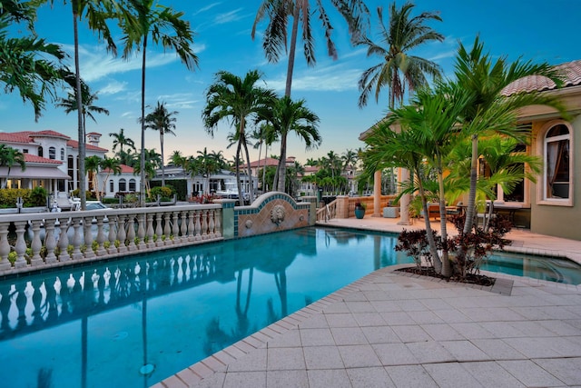 pool at dusk with a patio area