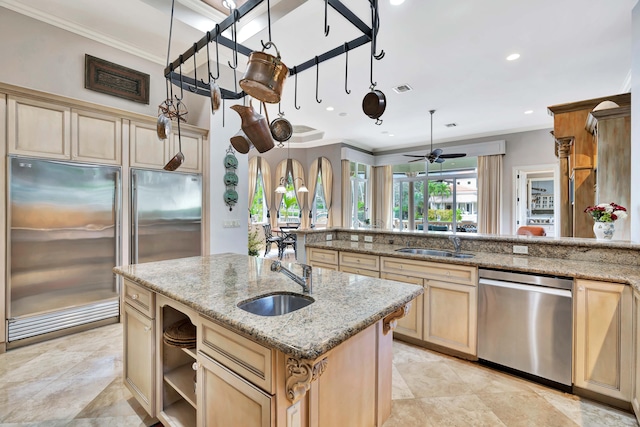 kitchen featuring a center island with sink, light stone countertops, sink, and appliances with stainless steel finishes