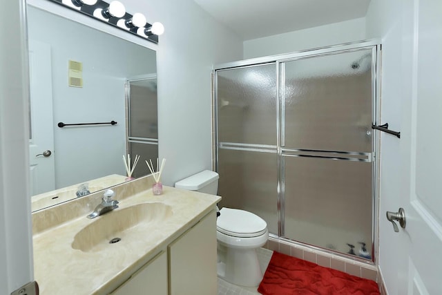 bathroom with tile patterned flooring, a shower with door, vanity, and toilet