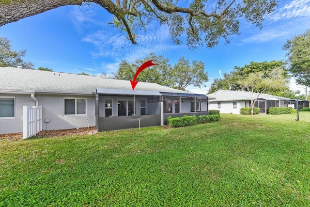 rear view of property featuring a sunroom and a yard