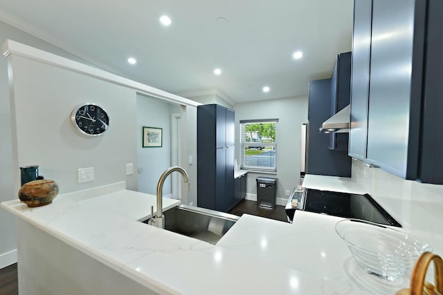 kitchen with kitchen peninsula, exhaust hood, light stone counters, and sink