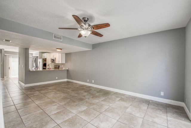 tiled empty room with a textured ceiling, ceiling fan, and sink