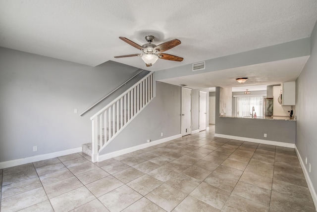 unfurnished living room with light tile patterned floors, a textured ceiling, ceiling fan, and sink