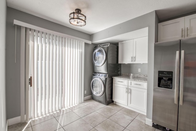 laundry room featuring light tile patterned flooring and stacked washer and clothes dryer