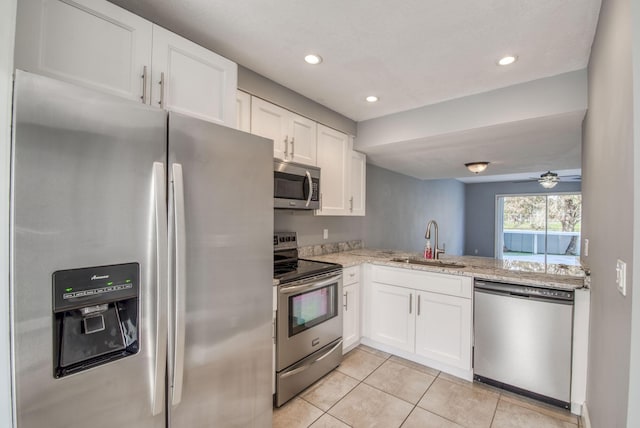 kitchen with light stone countertops, sink, white cabinets, and stainless steel appliances