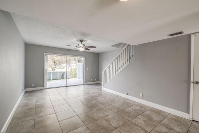 empty room with light tile patterned floors, a textured ceiling, and ceiling fan