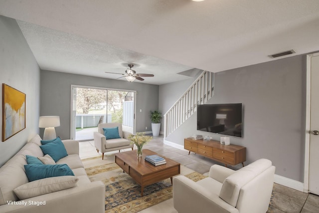 tiled living room featuring ceiling fan and a textured ceiling