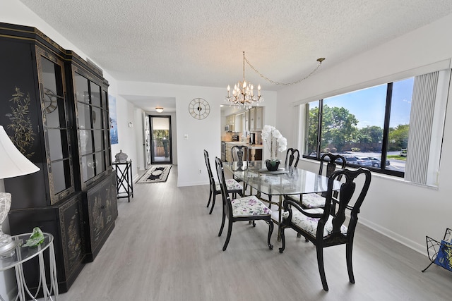 dining room with a chandelier, a textured ceiling, and light hardwood / wood-style floors