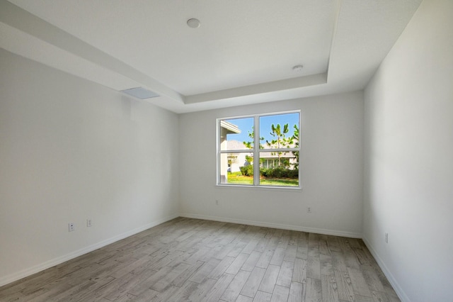 unfurnished room featuring a tray ceiling and light hardwood / wood-style flooring