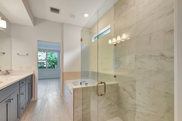 bathroom with hardwood / wood-style flooring, vanity, and plus walk in shower