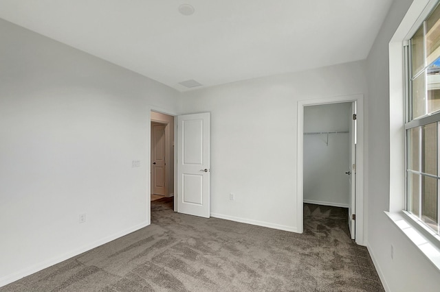 unfurnished bedroom with carpet flooring, a spacious closet, and a closet