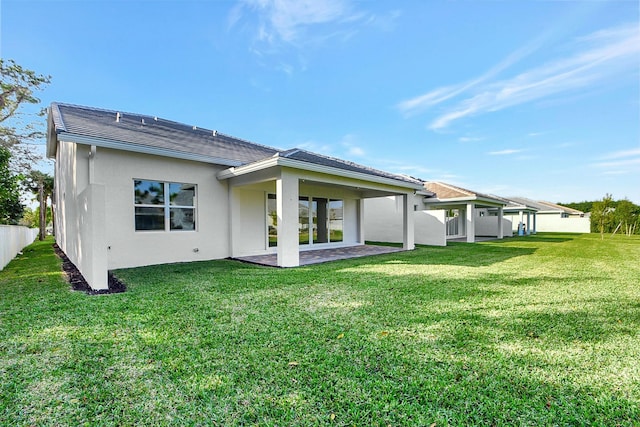 rear view of property featuring a yard and a patio area