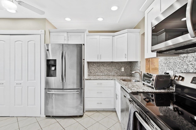 kitchen featuring white cabinets, light stone countertops, light tile patterned floors, tasteful backsplash, and stainless steel appliances