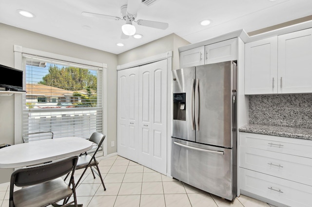 kitchen featuring white cabinetry, light stone counters, backsplash, stainless steel fridge, and light tile patterned flooring