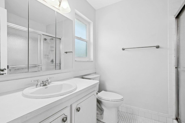 bathroom featuring tile patterned flooring, vanity, a shower with shower door, and toilet