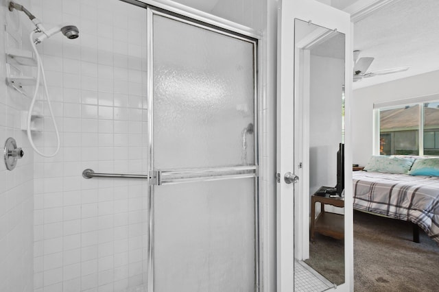 bathroom with ceiling fan and a shower with door