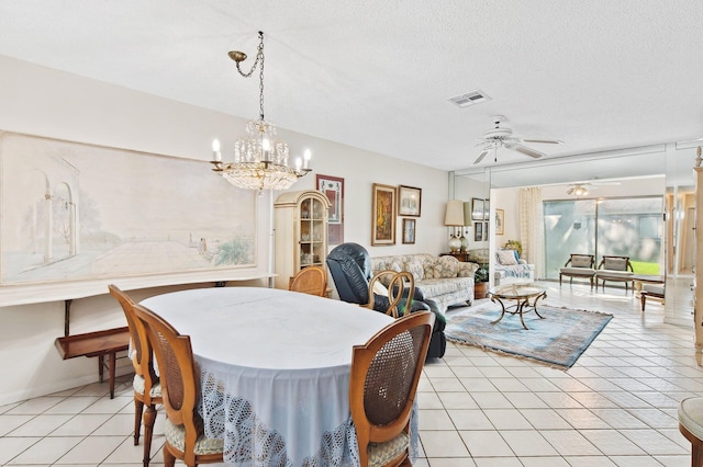 dining room with ceiling fan with notable chandelier, light tile patterned floors, and a textured ceiling