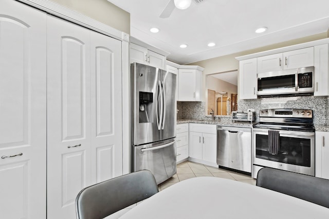 kitchen with backsplash, ceiling fan, light tile patterned floors, appliances with stainless steel finishes, and white cabinetry