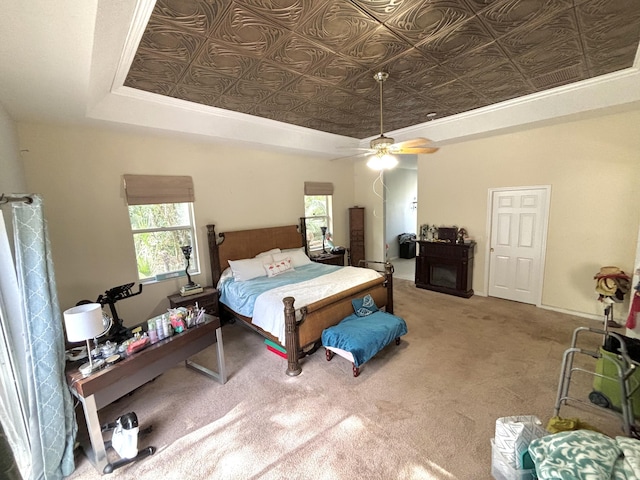 carpeted bedroom with ceiling fan, a raised ceiling, and ornamental molding