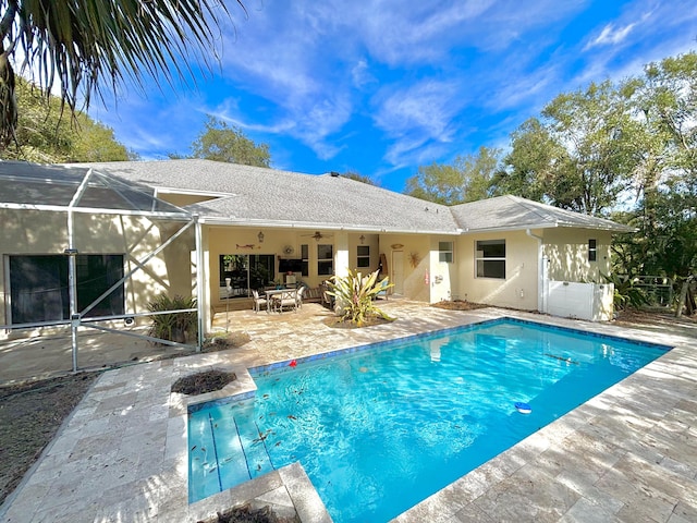 view of pool with a patio, glass enclosure, and ceiling fan