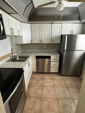 kitchen with white cabinets, sink, light tile patterned floors, and stainless steel appliances