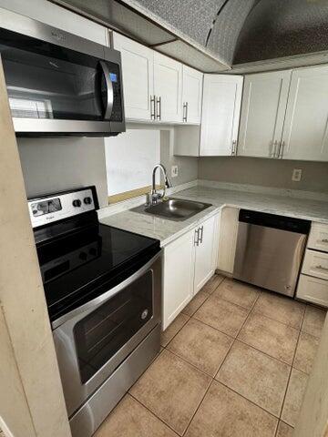 kitchen featuring white cabinetry, sink, light tile patterned floors, and stainless steel appliances