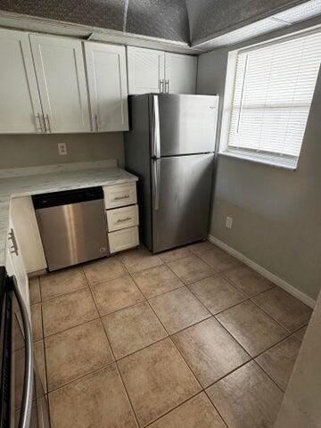 kitchen with white cabinets, light tile patterned floors, and appliances with stainless steel finishes