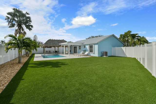 rear view of house featuring a fenced in pool, a patio area, a lawn, and central AC